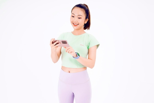 Young Asia lady show empty smart phone screen with positive expression smiles broadly dressed in casual clothing feeling happiness on blue background Mobile phone with white screen in female hand