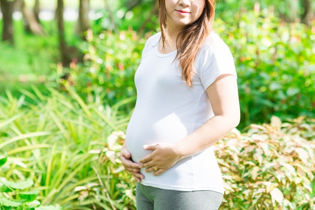 美しい庭園で妊娠中の若いアジア