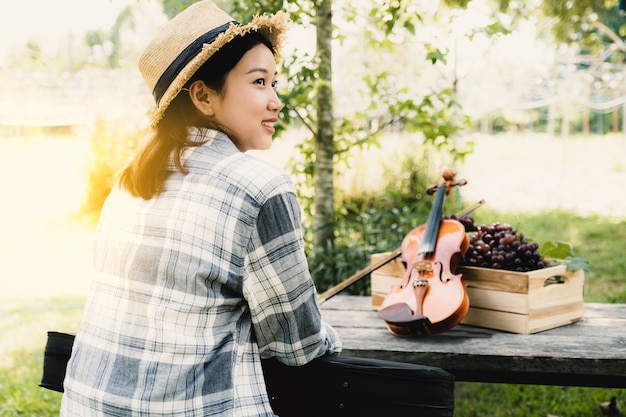 나무 상자에 바이올린과 포도를 넣은 젊은 아시아 여성 농부