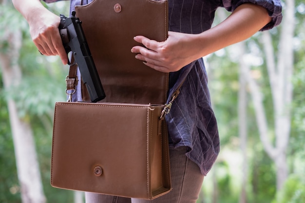 Young Asia woman putting a gun in her handbag