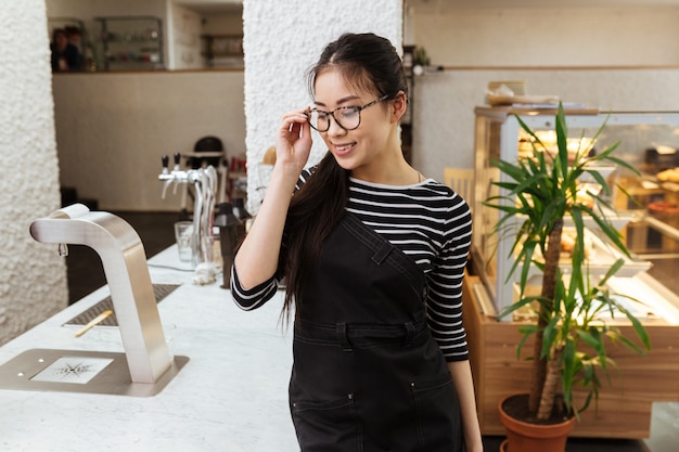 Young Asian barmaid in eyeglasses