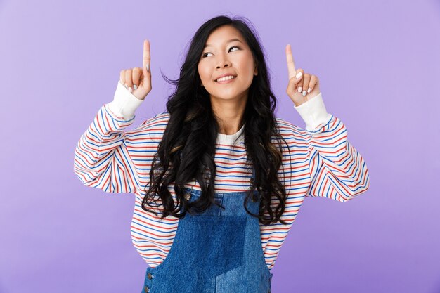 Young asian beautiful attractive woman posing isolated indoors pointing.