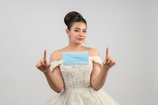 Young asian beautiful bride pose with face mask on white background