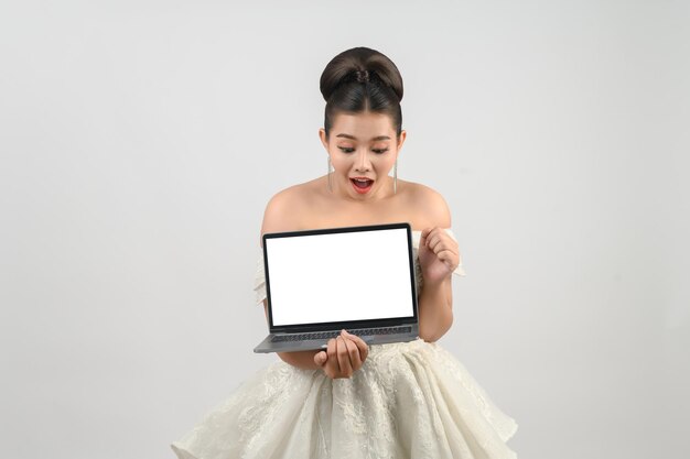 Foto giovane splendida sposa asiatica posa con un computer portatile in mano