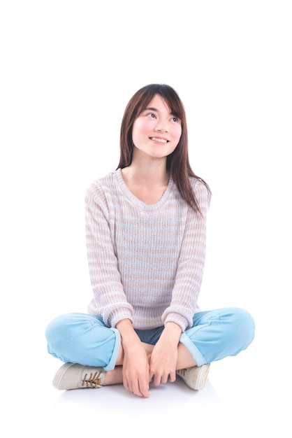 Young asian beautiful girl sitting on the floor and smiles over white background