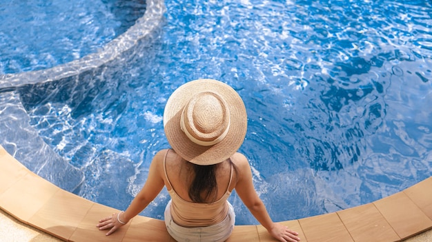 스파 리조트 수영장에서 편안한 젊은 아시아 아름다운 여성 수영장이 있는 아름다운 열대 해변 앞 호텔 리조트