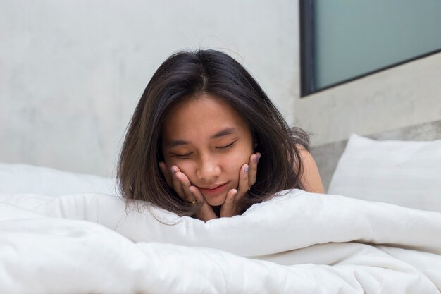 Giovane bella donna asiatica che dorme in camera da letto