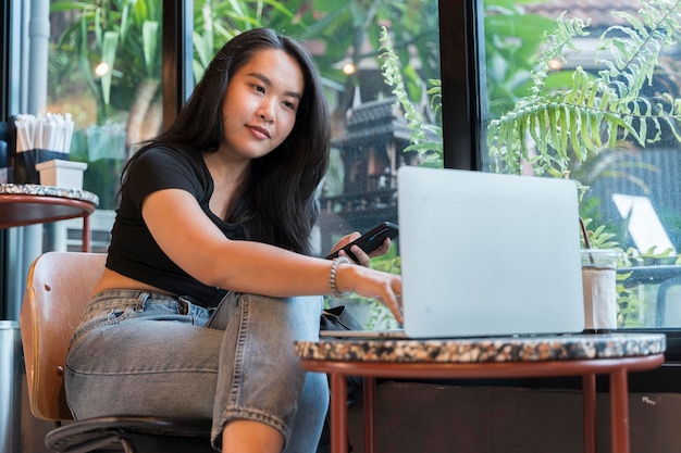 비즈니스 온라인 쇼핑 송금 금융 인터넷 뱅킹을 위해 스마트폰과 노트북을 사용하는 젊은 아시아 미녀