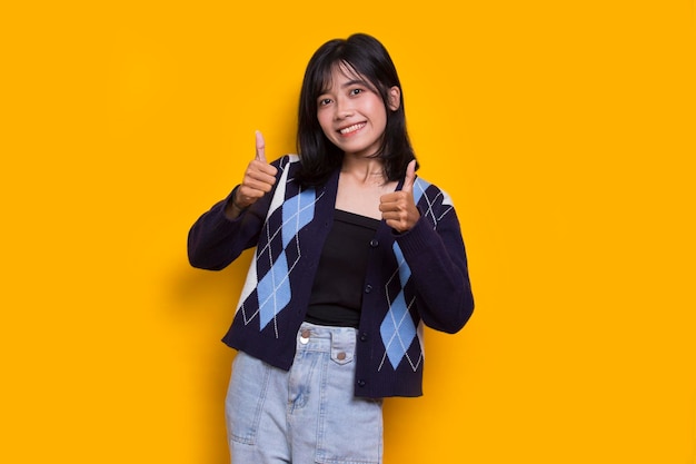 young asian beautiful woman with ok sign gesture tumb up isolated on yellow background