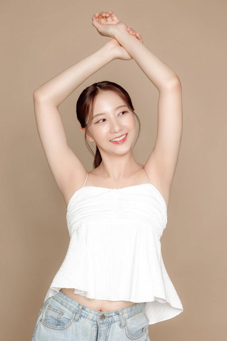 Photo 젊은 아시아 미녀는 얼굴에 한국식 화장을 하고 고립된 베이지색 배경의 완벽한 피부로 머리를 뒤로 뽑았습니다.