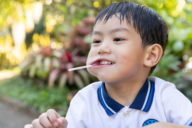 Young asian boy eating a lollipop