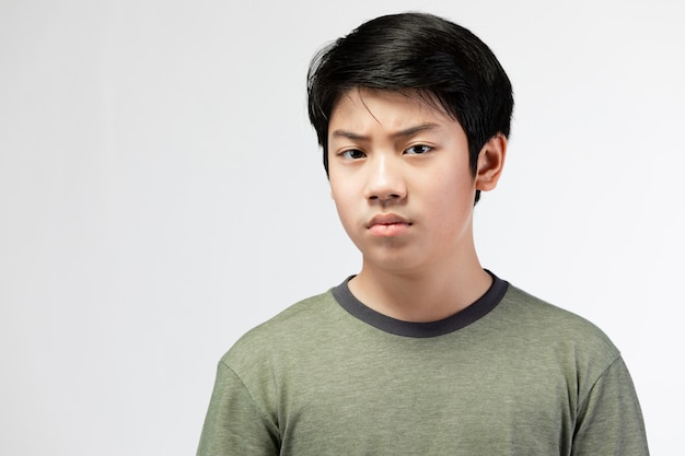 Young Asian boy over gray background, be upset; have a bad temper emotional.