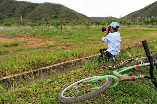 緑の果樹園の写真を撮る若いアジアの少年