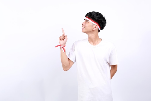 young asian boy with red white ribbon celebrating indonesia independence day while pointing above