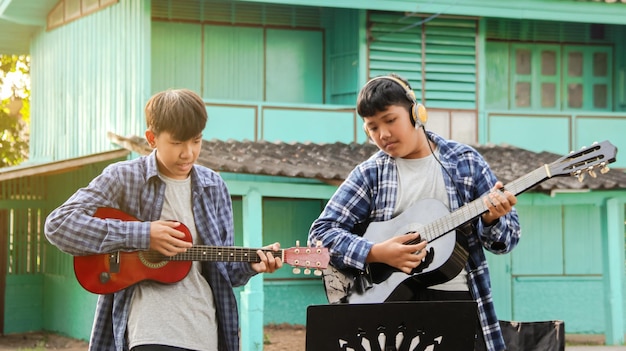 Foto giovani ragazzi asiatici suonano la chitarra acustica davanti a una casa