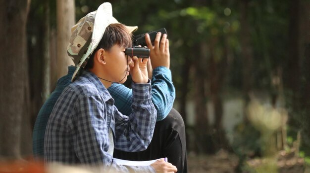 사진 아시아 의 어린 소년 들 은 현지 공원 에서 새 들 과 동물 들 을 감시 하기 위해 안경 을 사용 하고 있다