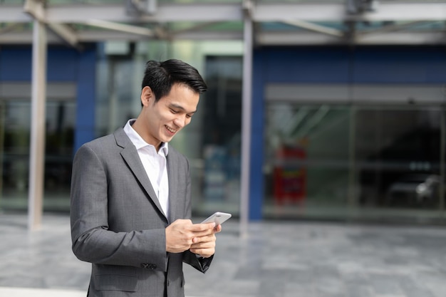 Young Asian business man smile holding smart phone at office areaman smart business concept