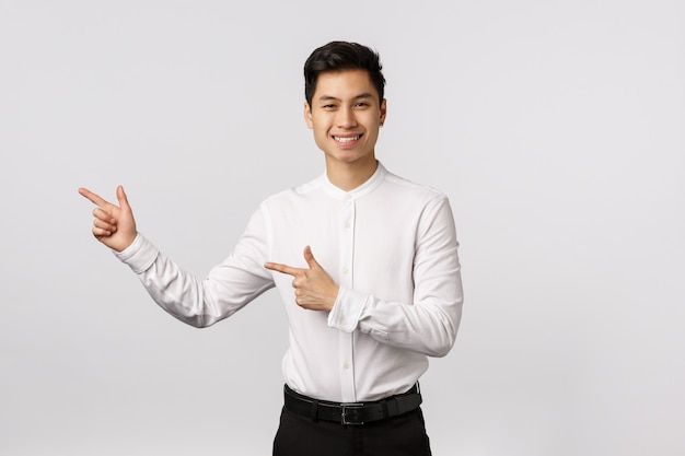 Young asian business man in a suit pointing with his finger on the.