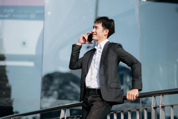 Photo young asian business man working at outside business center with laptop tablet smartphone and taking notes on the paper in city