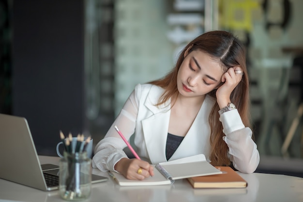 Giovane donna asiatica di affari che si sente male e stanca o esausta dal lavoro d'ufficio.