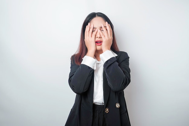 Young asian business woman isolated on white background looks\
depressed face covered by fingers frightened and nervous