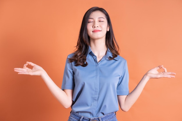 Young Asian business woman posing on orange background