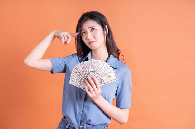 Young Asian business woman posing on orange background