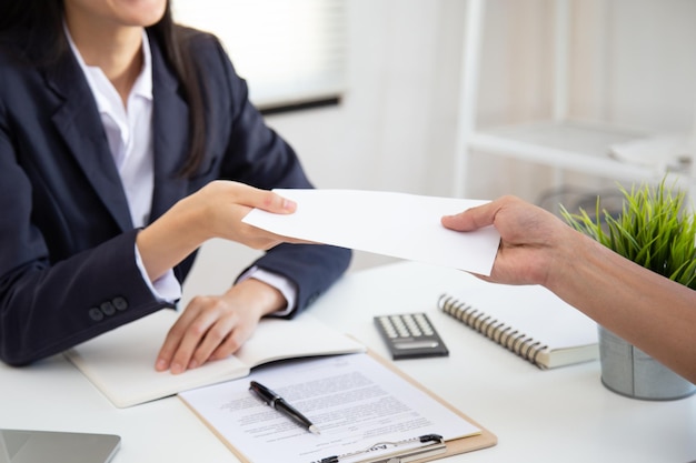 Young Asian business woman receiving salary or bonus money from boss or manager at office happily