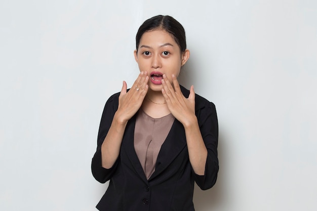 Young asian business woman shocked covering mouth with hands