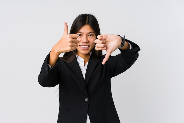 Young asian business woman showing thumbs up and thumbs down, difficult choose concept