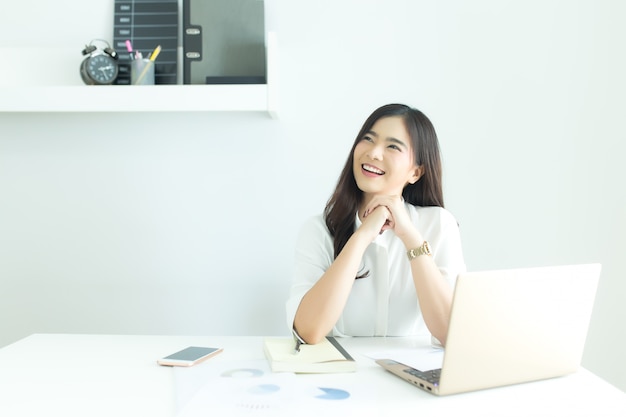 젊은 아시아 비즈니스 여자 웃 고 현대 사무실에서 책상에 작업에 대 한 아이디어를 생각.