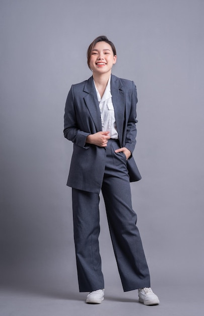 회색 배경에 서 있는 젊은 아시아 비즈니스 우먼