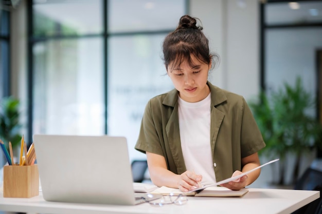 Giovane donna asiatica di affari o studente che lavora online sul computer portatile