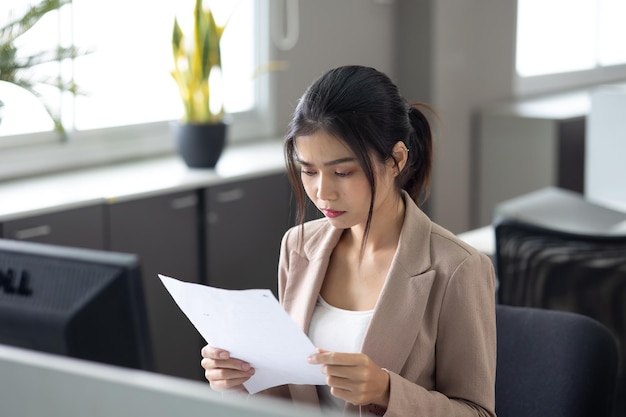 현대 홈 오피스에서 데스크톱 컴퓨터로 책상에서 일하는 젊은 아시아 비즈니스 여성