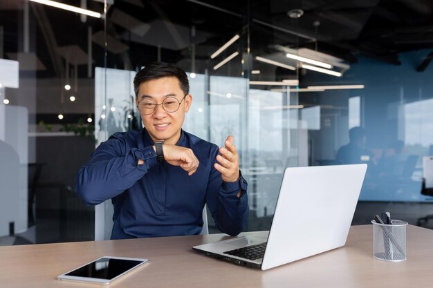 A young asian businessman a freelancer works in the office using a laptop he talks through the smart