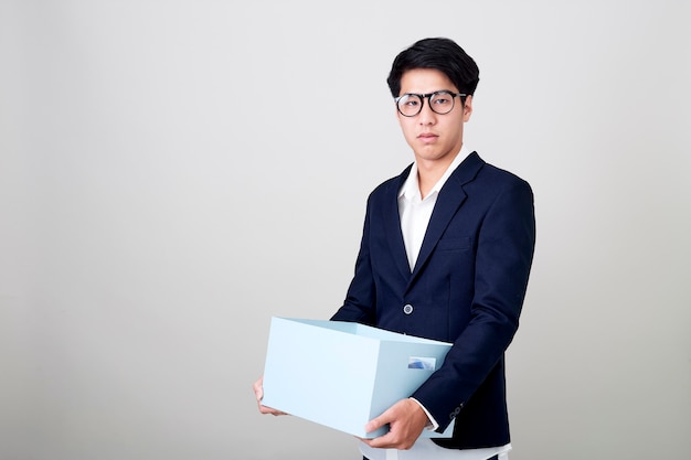 Молодой азиатский бизнесмен держа коробку
