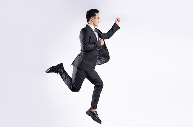 Young Asian businessman jumping on white