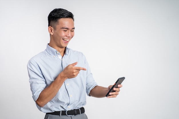 Young asian businessman laughing while looking at his phone