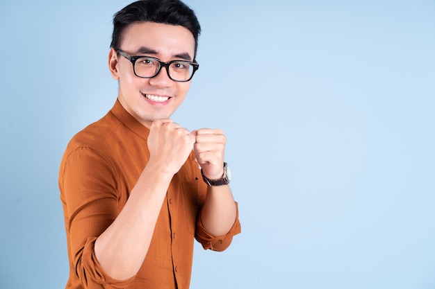 Young Asian businessman posing on blue background