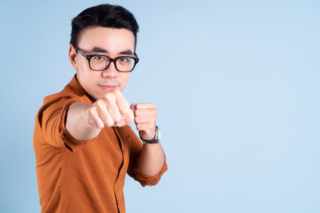 Young Asian businessman posing on blue background