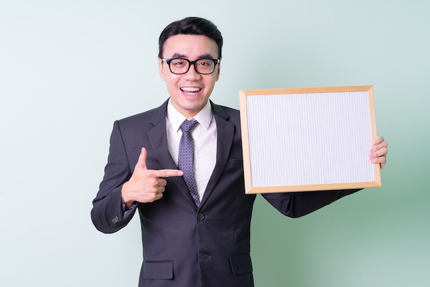 Young Asian businessman posing on green background