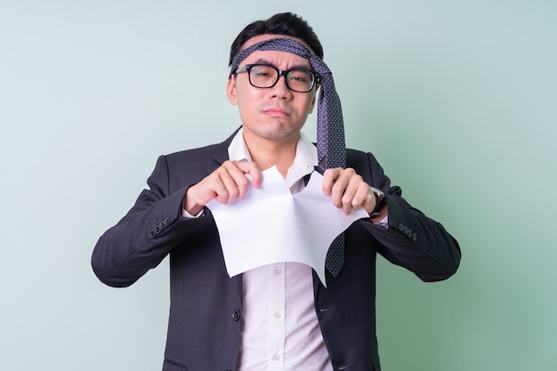 Young Asian businessman posing on green background