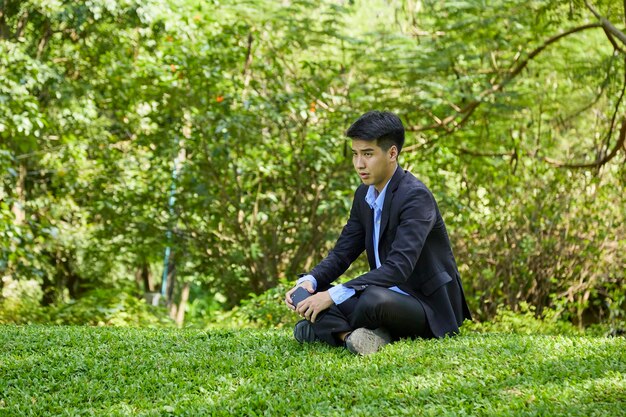 A young asian businessman relaxing in a nature park