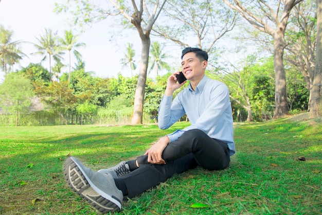 Young asian businessman relaxing while talking on mobile phone 