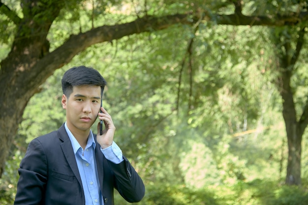 Молодой азиатский бизнесмен, сидя в парке