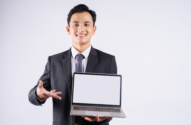 Молодой азиатский бизнесмен, используя ноутбук на белом