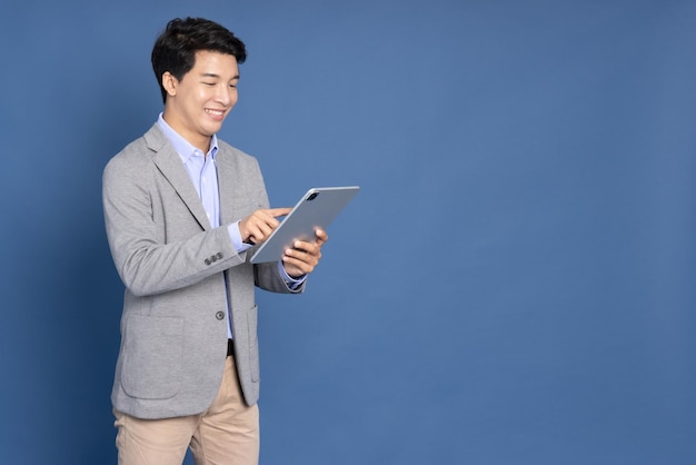 Young Asian businessman using tablet on hand isolated on blue background