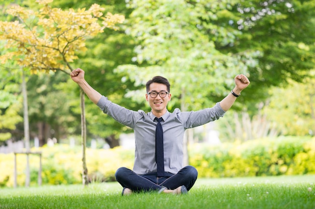 Young asian businessman using tablet, mobile phone in the park