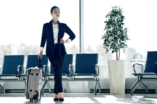 Young asian businesswoman at the airport with trolley