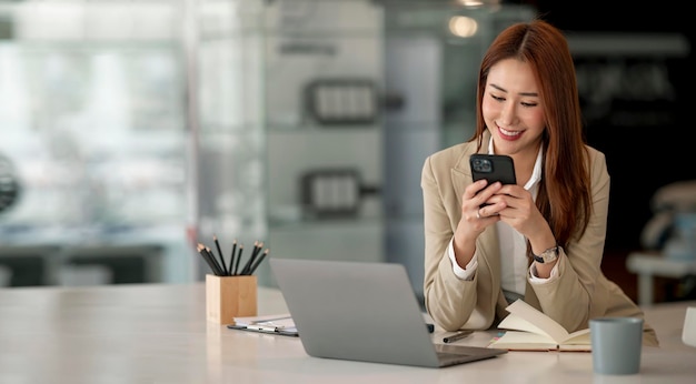 젊은 아시아 사업가 아름다운 매력적인 미소와 사무실에 앉아 휴대 전화에 얘기